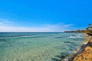 A beach with clear water, a stone walkway, and palm trees. - Papakea | Ocean View 7 BR, Sleeps 20 | Car Incl. w/ 6+ Nights | PKC ML-3966 by KBM (Lahaina)