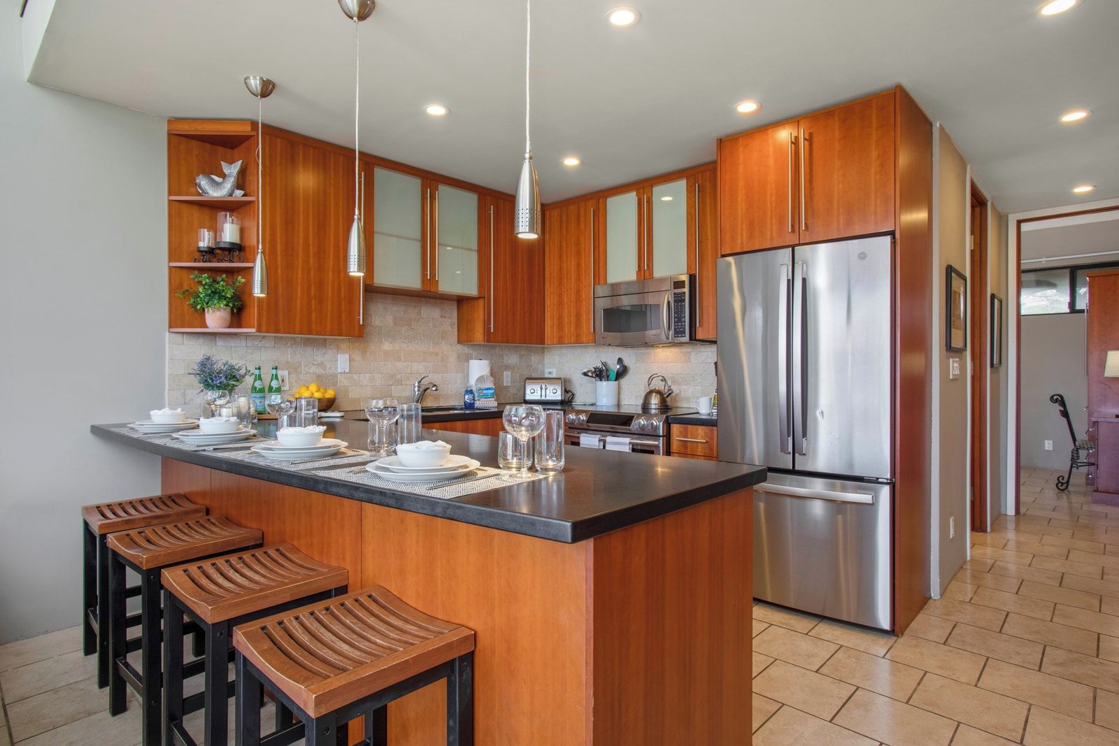 A modern kitchen with wooden cabinets, stainless steel appliances, and a central island with bar stools.