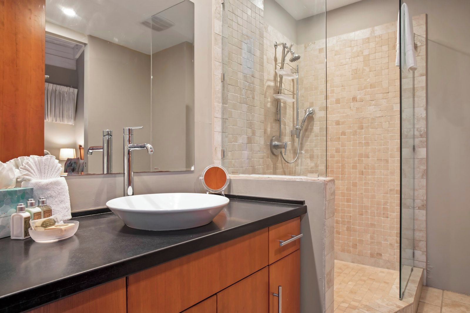 Une salle de bain avec un lavabo rond, un miroir, une douche avec une porte en verre et un porte-serviettes.