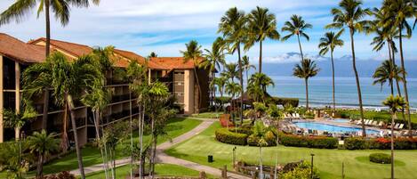 A resort with a pool, palm trees, and a view of the ocean.