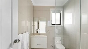 Un baño moderno con cabina de ducha de vidrio, un inodoro y un lavabo con espejo.