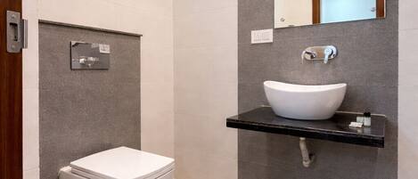 Een moderne badkamer met toilet, wandverwarming, wastafel met spiegel en douchekop.
