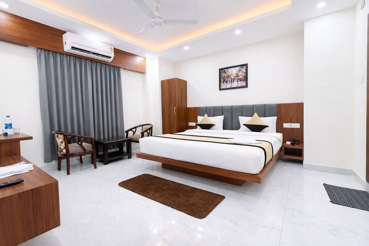 Habitación de hotel moderna con cama, escritorio, sillas y unidad de aire acondicionado.