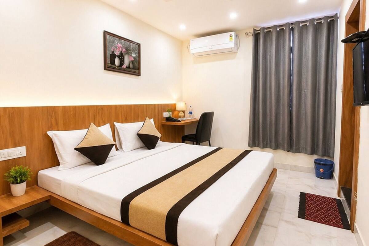 Una habitación de hotel moderna con cama, mesita de noche, lámpara, aire acondicionado y televisión.