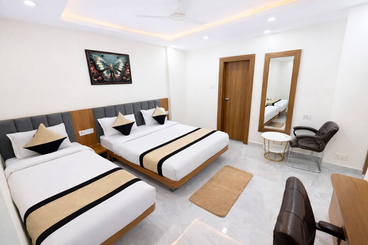Habitación de hotel con dos camas, un sillón de masaje, una mesita y un espejo.
