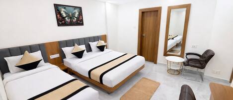 Habitación de hotel con dos camas, un sillón de masaje, una mesita y un espejo.