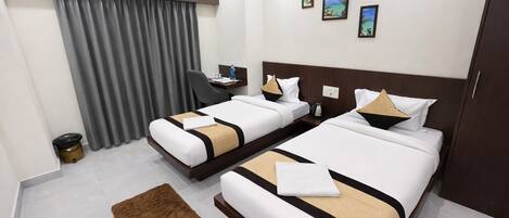 A hotel room with two beds, a desk, an air conditioner, and a view of the beach.