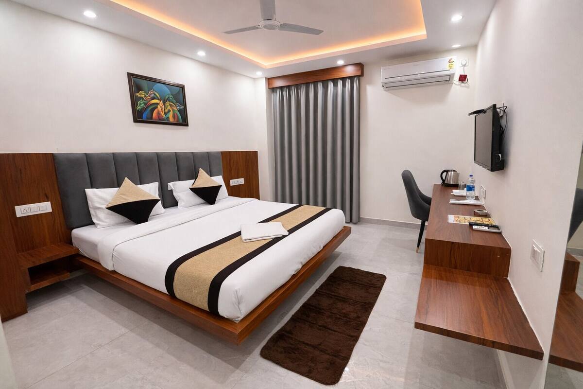 Una habitación de hotel moderna con cama, escritorio, silla y obras de arte.