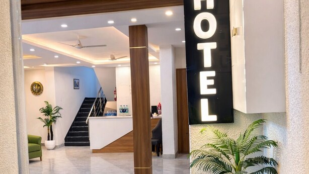 Eingangsbereich des Groves Hotel mit einer Rezeption, einer Treppe und einer großen Pflanze in einem Topf.