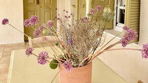 A potted plant with purple flowers on a table in a room with a door and window with shutters. - Gaea Pylos: Spacious family house near beaches (Pylos Nestoros)