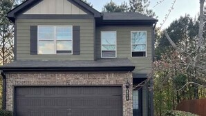 A two-story house with a garage, a front porch, and a driveway.
