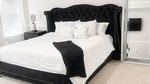 A bedroom with a bed, a nightstand, a lamp, a ceiling fan, and a large mirror.