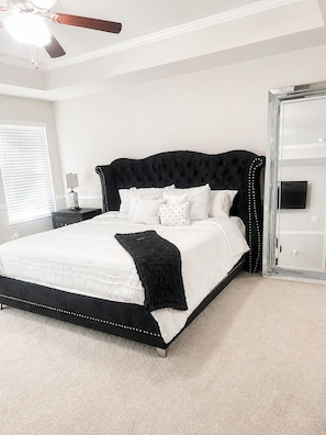 A bedroom with a bed, a nightstand, a lamp, a ceiling fan, and a large mirror. - Cozy Luxe Retreat with Warm Charm. WORLD CUP READY. 10 MINUTES FROM AIRPORT. (Union City)