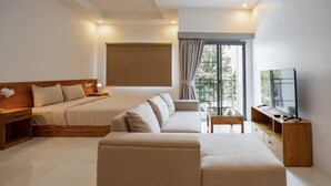 Quarto de hotel moderno com cama, sofá, TV e varanda com vista.