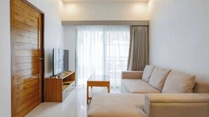 Uma sala de estar moderna com sofá, televisão, porta de madeira e janela com cortinas.