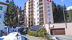 Ein mehrstöckiges Gebäude mit Balkonen, einer Flagge und einem mit Schnee bedeckten Untergrund.
