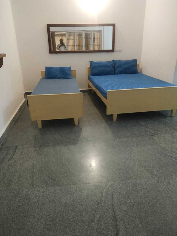 Una stanza con due letti singoli, uno specchio e una finestra con sbarre.