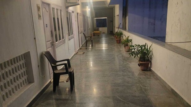 Un couloir avec un banc, des plantes en pot et un mur bleu.