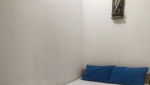 Un lit simple avec un cadre en bois, une literie blanche et des oreillers bleus.