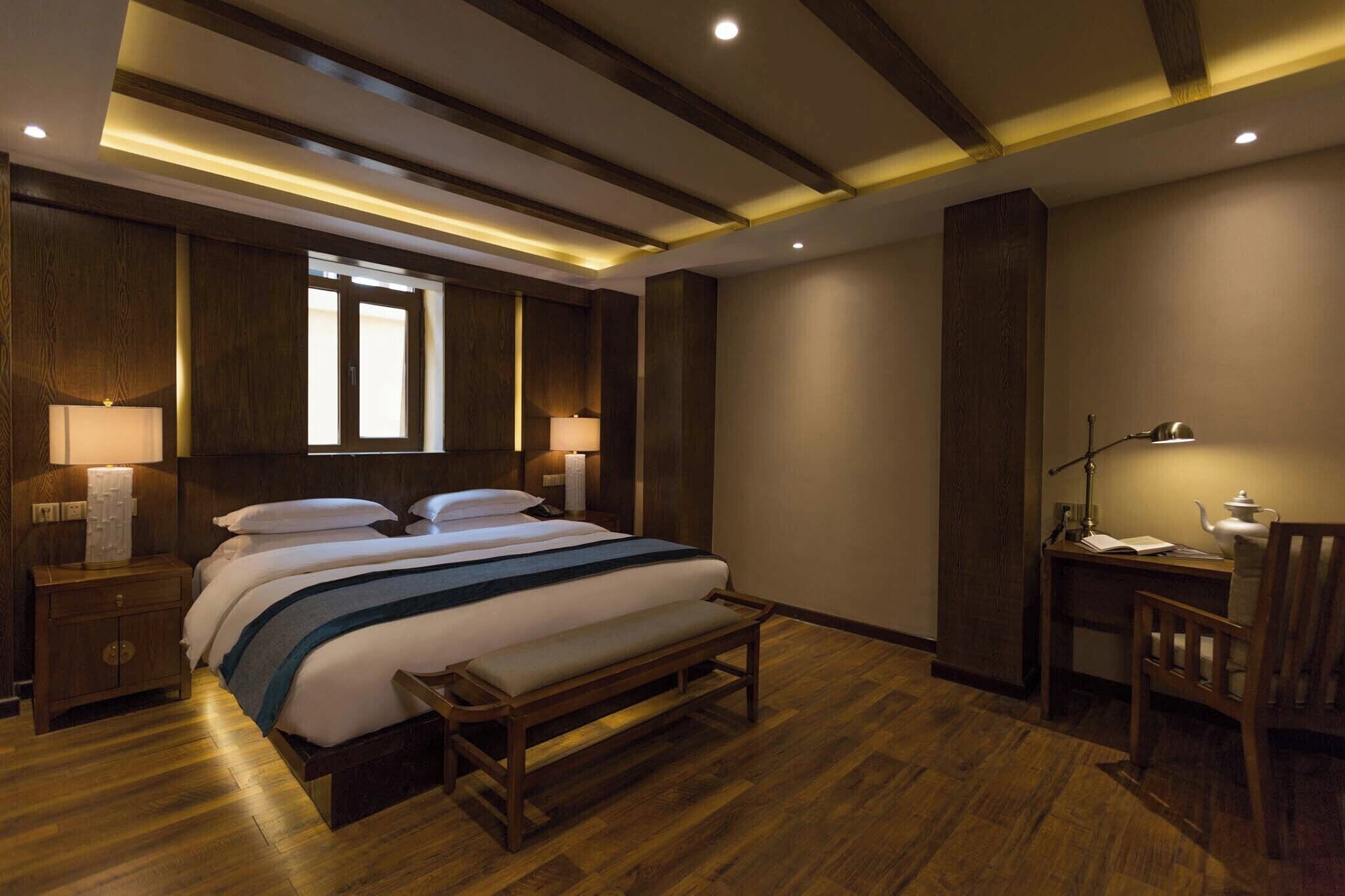 Ein Hotelzimmer mit einem großen Bett, Nachttischlampen, einem Schreibtisch und einem Sessel.