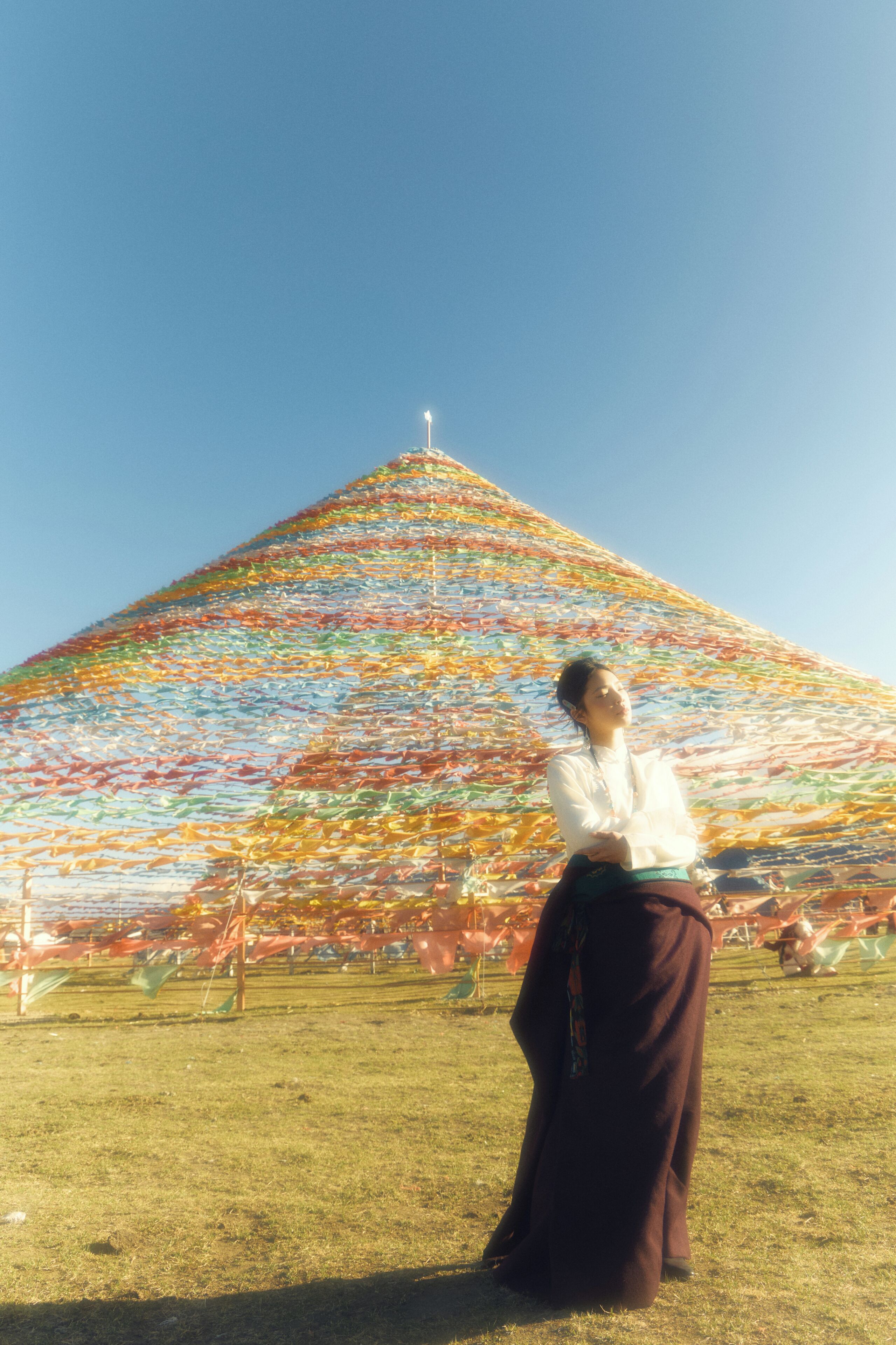 Una persona de pie frente a una estructura grande, colorida y triangular con una cruz en la parte superior.