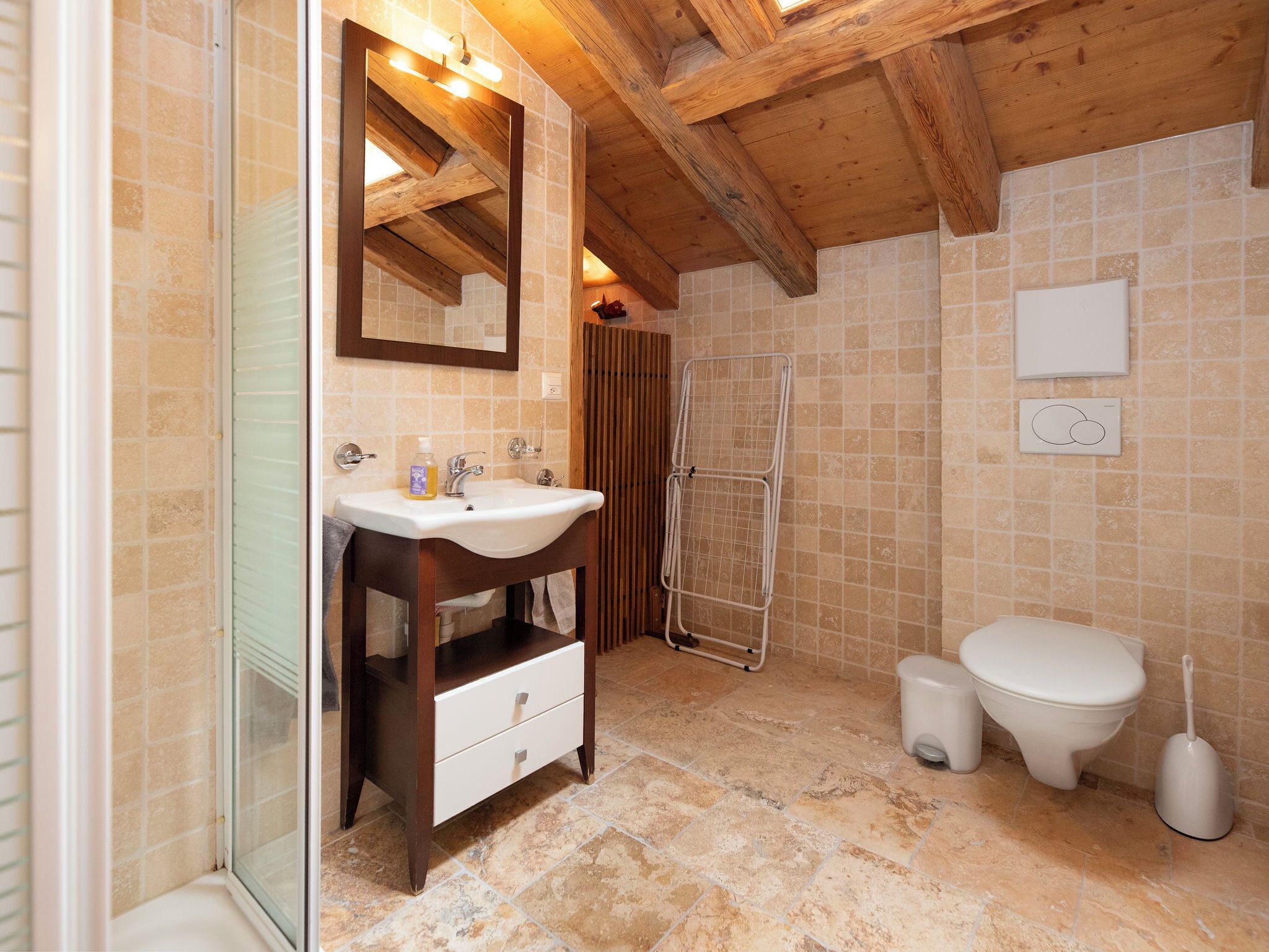 Ein Badezimmer mit Holzboden, einem Waschbecken mit Spiegel, einer Dusche und einer Toilette.