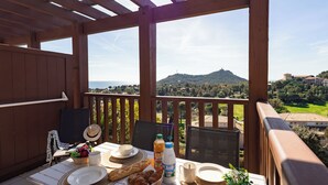 En træterrasse med et bord dækket til morgenmad, med udsigt over et smukt landskab.