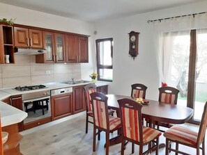 Eine Küche mit Holzausstattung, einem Gasherd, einer Spüle und einem Essbereich mit Stühlen und einem Tisch.