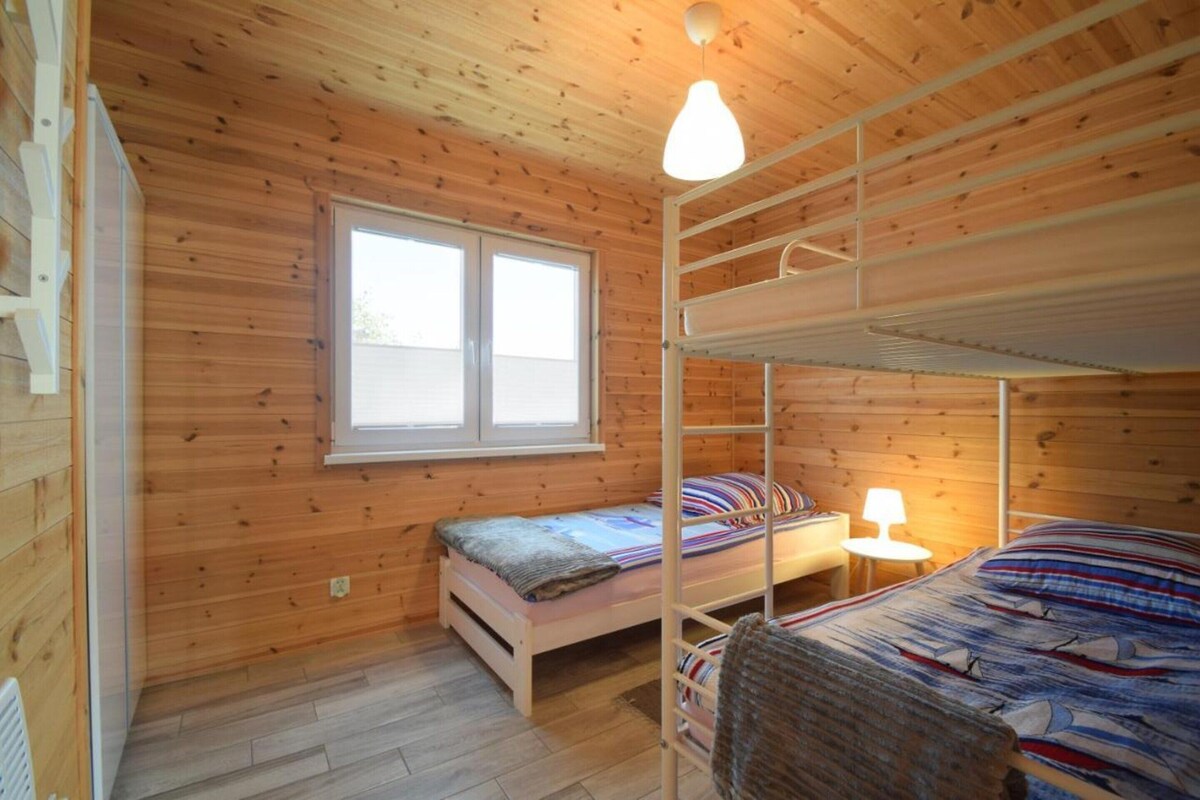 Eine Holzhütte mit Etagenbetten, einem Fenster und einer Lampe.