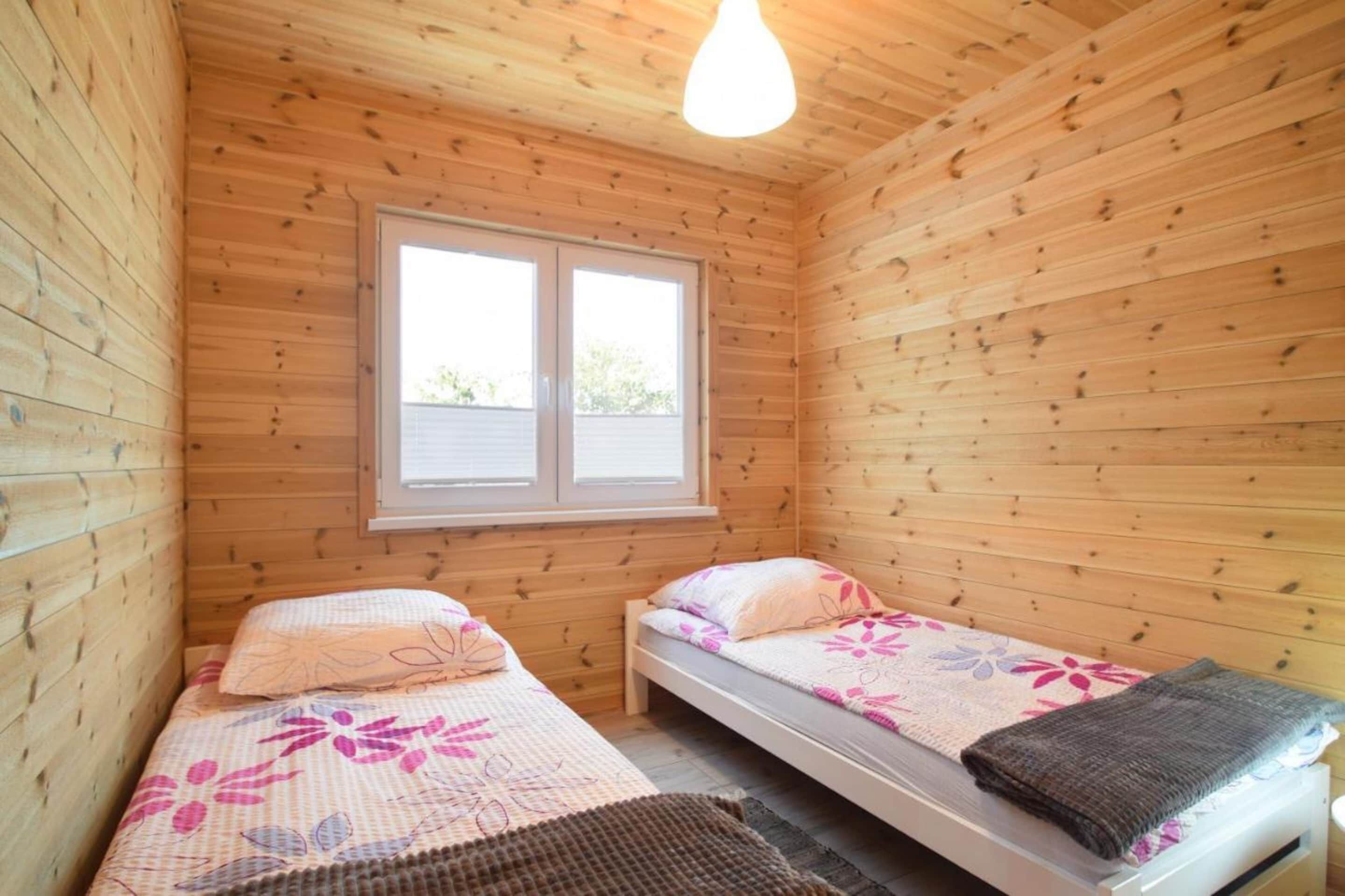 A small cabin with two wooden beds, a window, and a hanging light fixture.