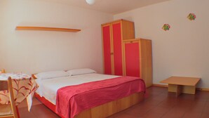 A bedroom with a bed, a desk, a chair, a wardrobe, and a small table. - Family Apartment in Olbia Near sea (Olbia)
