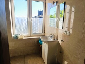 A bathroom with a window, a sink, and a mirror. - Apartment in Miedzyzdroje Near the Beach (Międzyzdroje)