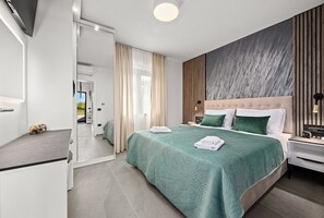 A modern hotel room with a large bed, a flat-screen TV, and a view of the outdoors. - Villa in Pula Near Hidrobaza Beach (Pula)