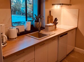 A modern kitchen with a window, a sink, a coffee maker, and a knife block. - Holiday Home With Sauna and Whirlpool (Międzyzdroje)