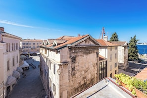 A courtyard with buildings, a crane, and a view of the sea. - Apartment in Pula Near City Center Waterfront (Pula)