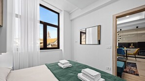 Et hotelværelse med en seng, et vindue med gardiner, et spejl og udsigt til det fri.