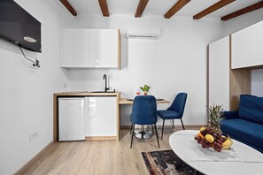 Ein kompakter Wohnraum mit Küchenzeile, Essbereich und einer Sitzecke mit Sofa und Sesseln.