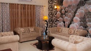 A living room with two sofas, a coffee table, and a wall with a textured design. - Rooms Near Centurus Mall islamabad (Islamabad)