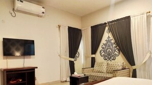 A hotel room with a bed, a TV, a sofa, and curtains. - Rooms Near Centurus Mall islamabad (Islamabad)