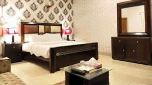A bedroom with a bed, bedside tables, a dresser, a mirror, and a glass coffee table. - Rooms Near Centurus Mall islamabad (Islamabad)