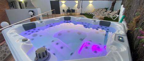A hot tub with a built-in heater, surrounded by lounge chairs and a patio area.