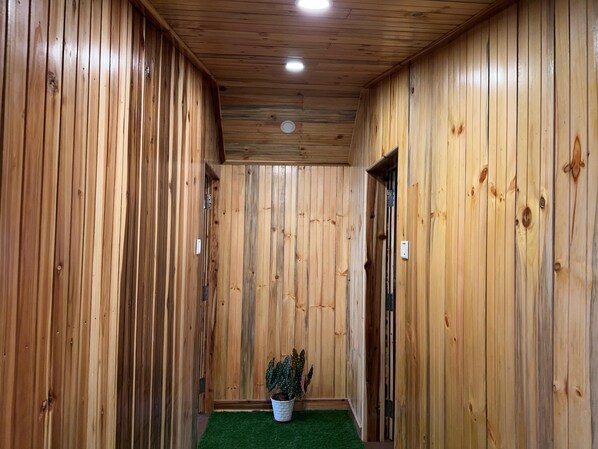 A wooden hallway with a potted plant and a door. - Hotel Basera (Darjeeling)