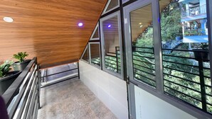 A modern interior with wooden ceiling, large windows, and a balcony with a view of greenery.