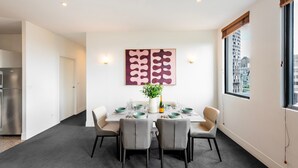Un comedor moderno con una mesa dispuesta para cuatro, una planta en maceta y vistas de la ciudad a través de un ventanal.
