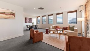 Una sala de estar moderna con un sofá, sillones, una zona de comedor y ventanas amplias.