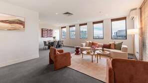 A modern living room with a sofa, armchairs, a dining area, and large windows. - Southside Serenity Pool, Gym & Tennis (Southbank)