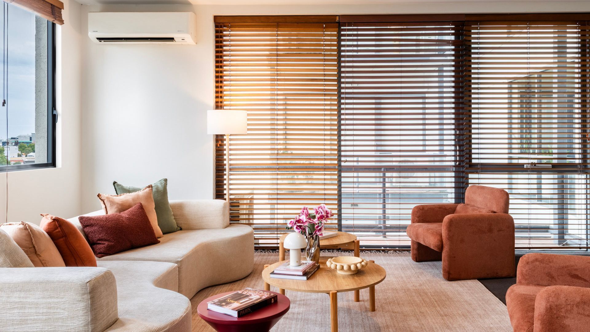 A modern living room with a sofa, armchair, and a coffee table with books and a vase.
