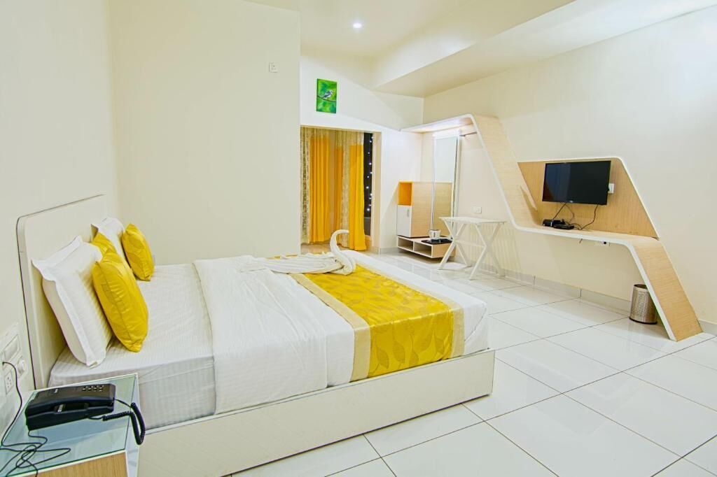 Camera d'albergo con un letto, una scrivania con televisore, uno specchio e un piccolo tavolino.