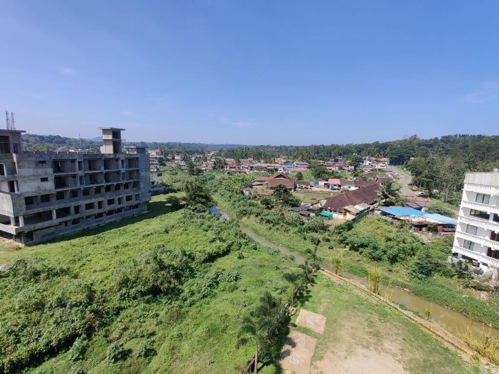 A residential area with a large building under construction, a river, and surrounding greenery.
