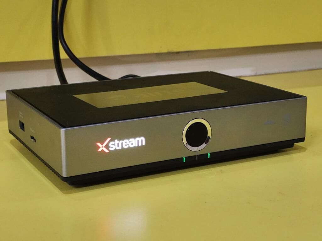 A black and silver Xstream device with a circular port on a yellow surface.